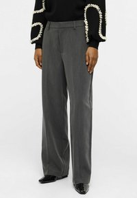 Pantalons gris ajustés avec une coupe droite, présentant de légères rayures, une texture lisse et une fermeture plate à l'avant.