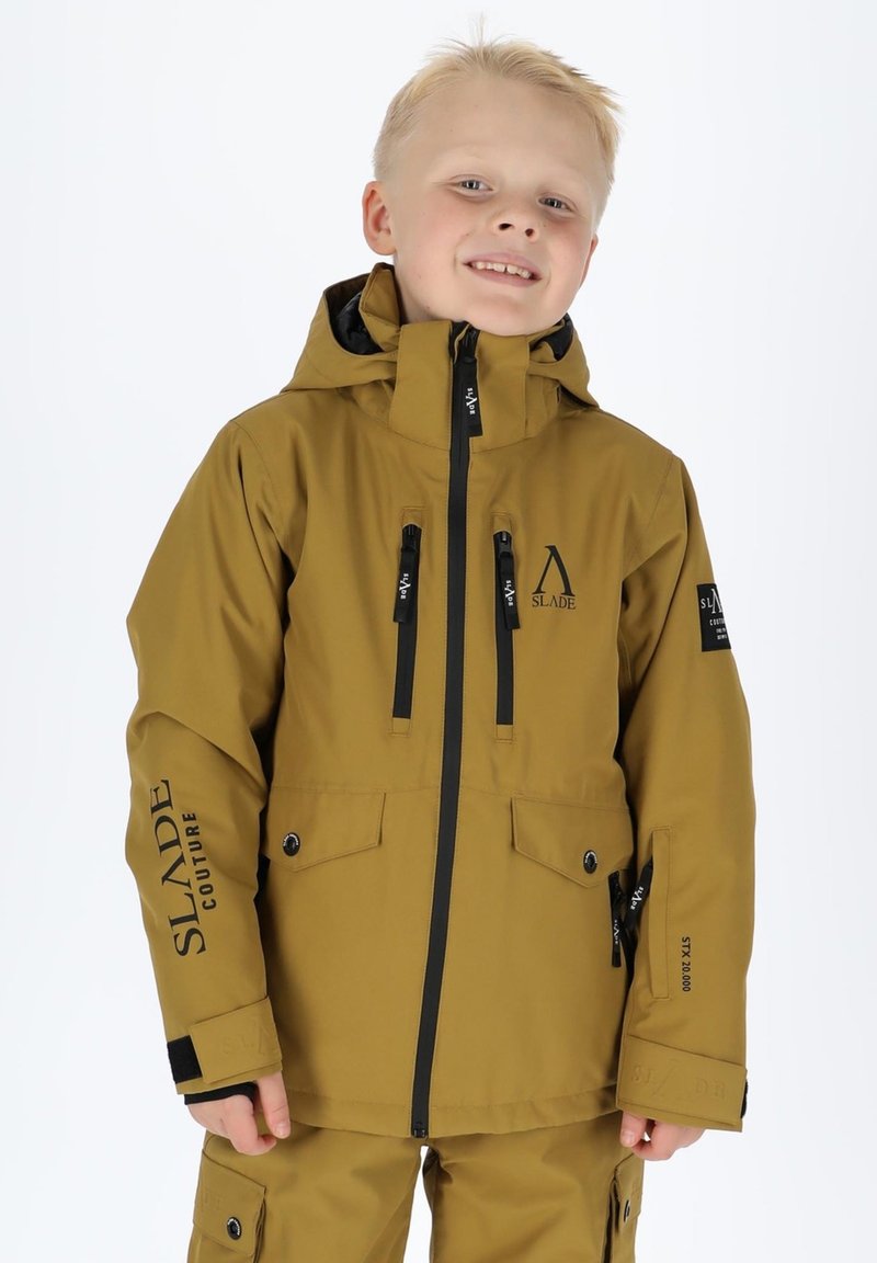 Braune wasserdichte Jacke mit schwarzen Reißverschlüssen und Details, ausgestattet mit zwei Brusttaschen und einem Logo. Der Kragen hat eine vollständig angenähte Kapuze.