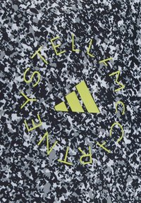 Black and white speckled fabric features a bold green text reading "STELLA McCARTNEY" and a yellow Adidas logo with three stripes.