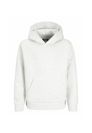Garçon debout, souriant de profil, portant un sweat à capuche blanc, un jean bleu ample et des chaussures beiges sur un fond clair uni.