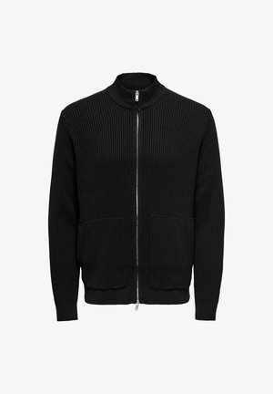 Mustriline musta riidekardigan kõrge krae, kahe esipocketiga ja tihedalt istuvate varrukatega. Valmistatud tekstureeritud kudumaterjalist.