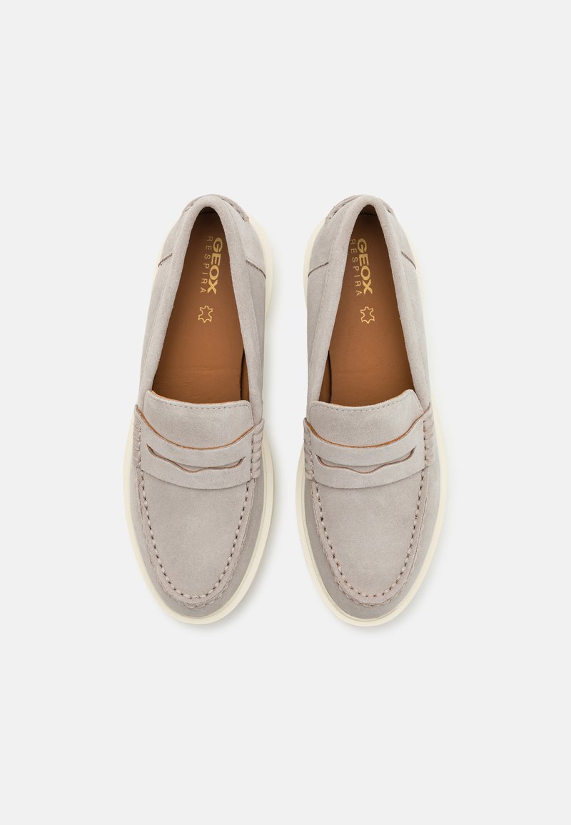 Mocasines de ante gris con suela de goma blanca, que presentan costuras decorativas y un sutil acento marrón claro a lo largo del empeine.