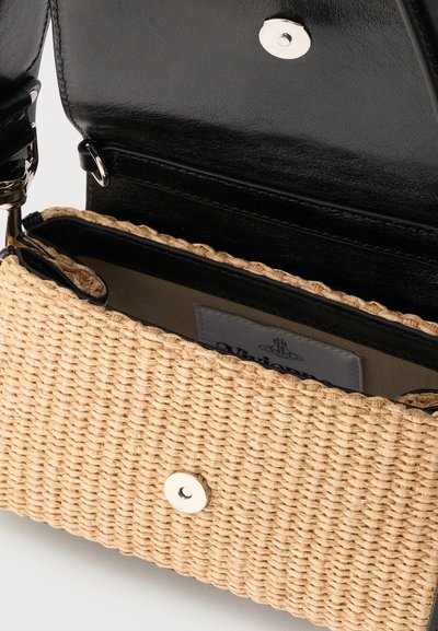 Πλεκτή μπεζ τσάντα χειρός με μαύρο δερμάτινο εσωτερικό και καπάκι, ανοιχτή για να δείχνει το ασημένιο μαγνητικό κούμπωμα και την υφασμάτινη ετικέτα στο εσωτερικό.