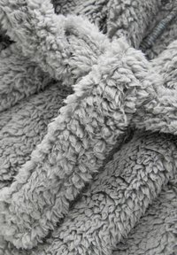 Grau kuschelige Decke mit einer weichen, flauschigen Textur und variierenden Florlängen für zusätzliche Wärme und Komfort. Keine sichtbaren Muster oder Akzente.