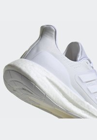 Białe buty do biegania z teksturowaną cholewką, amortyzacją Boost oraz gumową podeszwą z detalicznym wzorem. Czysty i nowoczesny design.