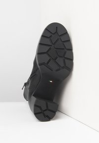 Suela de bota de cuero negro con profundos dibujos geométricos, cremallera lateral y la marcación "NeroGiardini Hecho en Italia" con la bandera italiana.