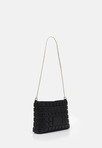 Black quilted handbag made of synthetic material, featuring a silver chain strap and a rectangular patch detail on the front.