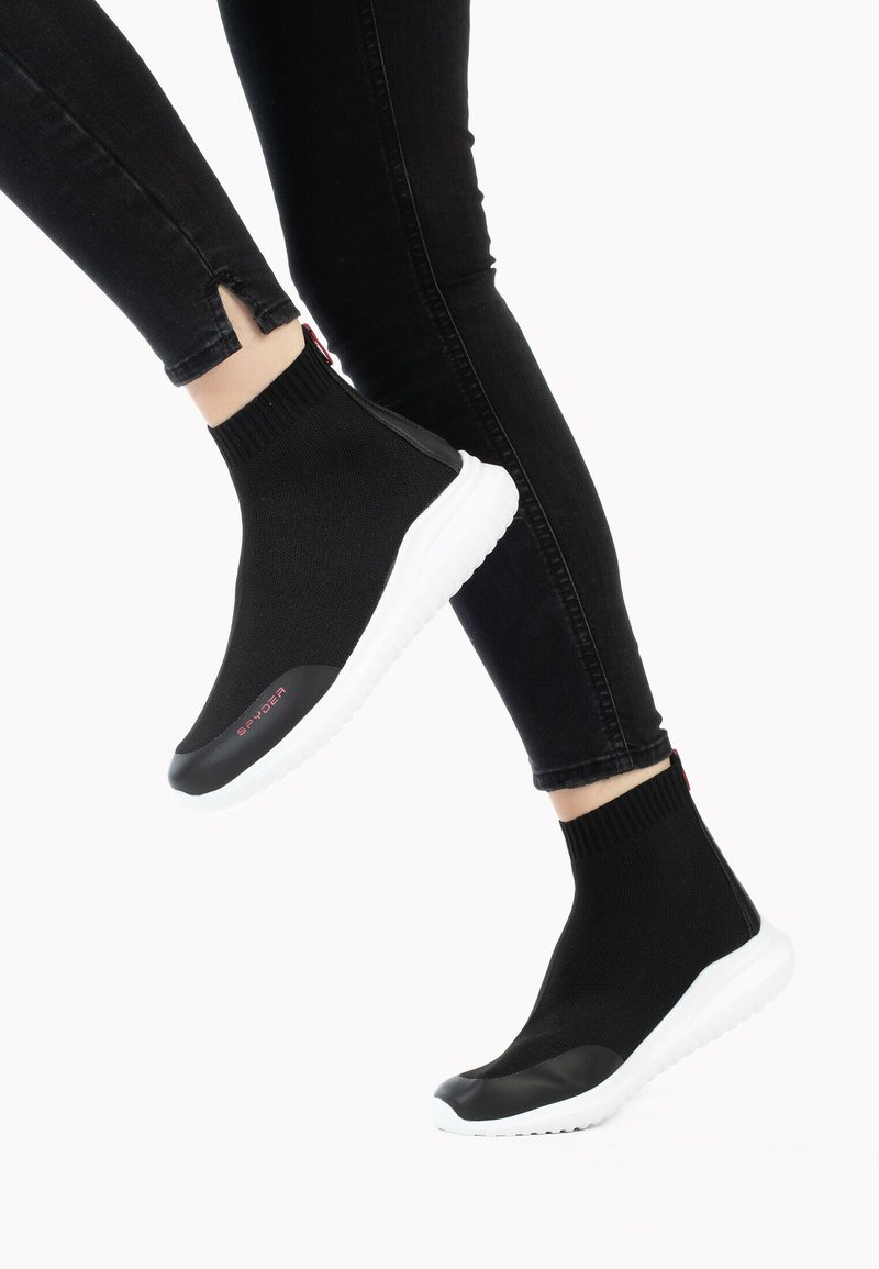 Czarne buty typu slip-on z plecionym wierzchem i białą gumową podeszwą; wyróżniają się kontrastującą, czarną osłoną palców oraz czerwonym detalem z logo.