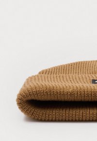 Gorro de malha castanho com textura canelada, dobrado na aba. Apresenta uma pequena etiqueta de logotipo preta na frente.
