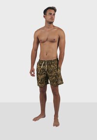 Bañador de estampado paisley en negro y dorado con cinturilla elástica y detalles con cuerda, hecho de tejido ligero.