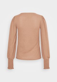 Haut à enfiler marron clair avec manches longues bouffantes et poignets froncés, présentant un col large et un corps ajusté avec une texture subtilement côtelée.