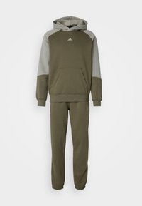 Completo felpa verde oliva con pantaloni, maniche raglan grigie. Presenta una tasca frontale e polsini elastici. Realizzato in morbido tessuto misto cotone.