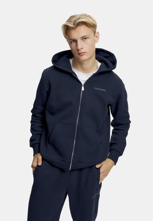 Mørkeblå zip-up hettegenser laget av en bomullsblanding, med en frontlomme, ribbede mansjetter og hette med snøring. Merkevarelogo på brystet.
