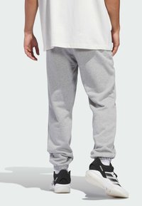 Γκρι βαμβακερές φόρμες με ελαστικά μανίκια, σε χαλαρή γραμμή, συνδυασμένες με ένα απλό λευκό μπλουζάκι. Μαύρα και λευκά αθλητικά παπούτσια.