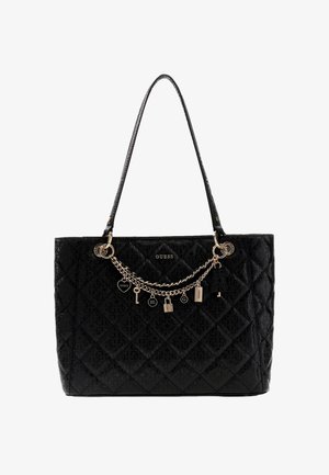 Sac à main matelassé noir de Guess avec une bandoulière unique et une chaîne dorée ornée de breloques et de détails de logo sur le devant.