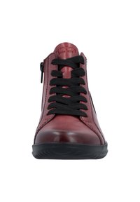 Chaussure montante en cuir rouge avec lacets noirs et zip sur le côté. Texture lisse, bout rond et semelle en caoutchouc noire. Nom de la marque embossé sur la languette.