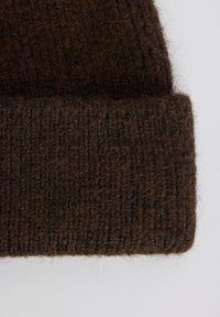 Gorro de punto marrón con textura acanalada y puño doblado, hecho de lana suave o una mezcla de lana, que muestra fibras irregulares y calidez.