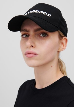 Casquette noire avec le texte blanc "LAGERFELD" à l'avant, en tissu. Elle présente une visière courbée et est accompagnée d'un t-shirt noir.