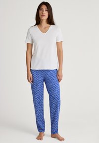 Witte V-hals T-shirt en blauwe gestreepte loungebroek met hartvormen. Zachte stof, relaxte pasvorm en korte mouwen zorgen voor een casual uitstraling.