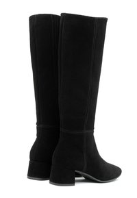 Crne zamšaste čizme do koljena sa četvrtastim potpeticama. Imaju vertikalne šavove i glatku gornju površinu. Zaobljen vrh i teksturirana podloga za prianjanje.