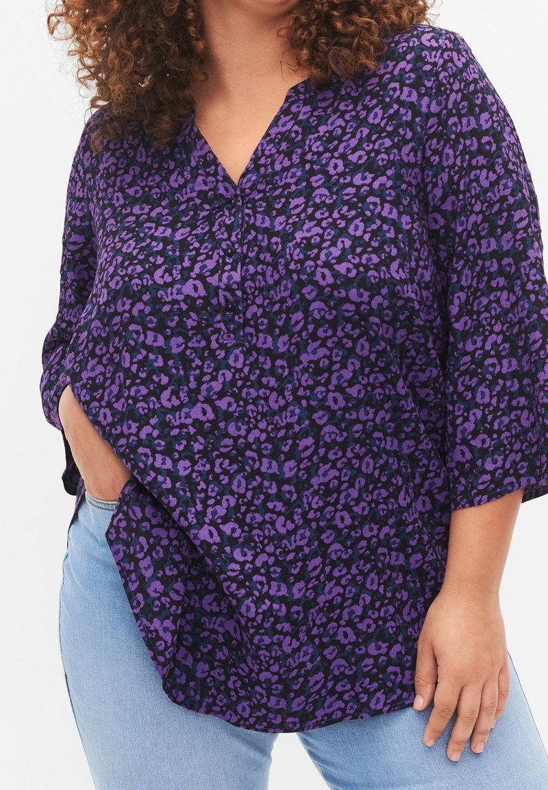Blouse à imprimé animal audacieux violet et noir avec encolure en V, manches aux trois quarts, coupe ample, fabriquée en tissu doux.