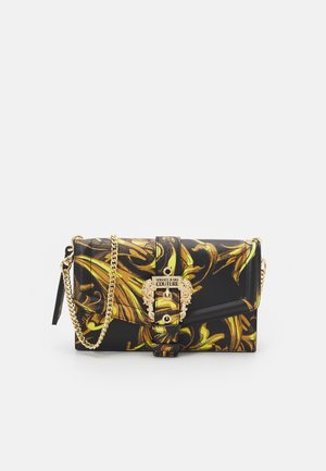 Bolso de mano negro con estampado floral amarillo, herrajes dorados y correa de cadena. Presenta un cierre de solapa con un broche decorativo y detalle del logo.