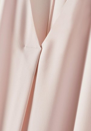 Lichtroze blouse met een gladde textuur, voorzien van een V-hals en een minimalistisch ontwerp. Subtiele stikdetails bij de halslijn.
