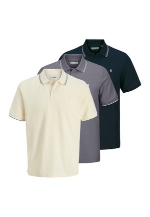 Drei Poloshirts ausgestellt: blassgelb, grau und marineblau, jeweils mit einem kontrastierenden Besatz am Kragen und an den Ärmeln, mit einem kleinen Logo.