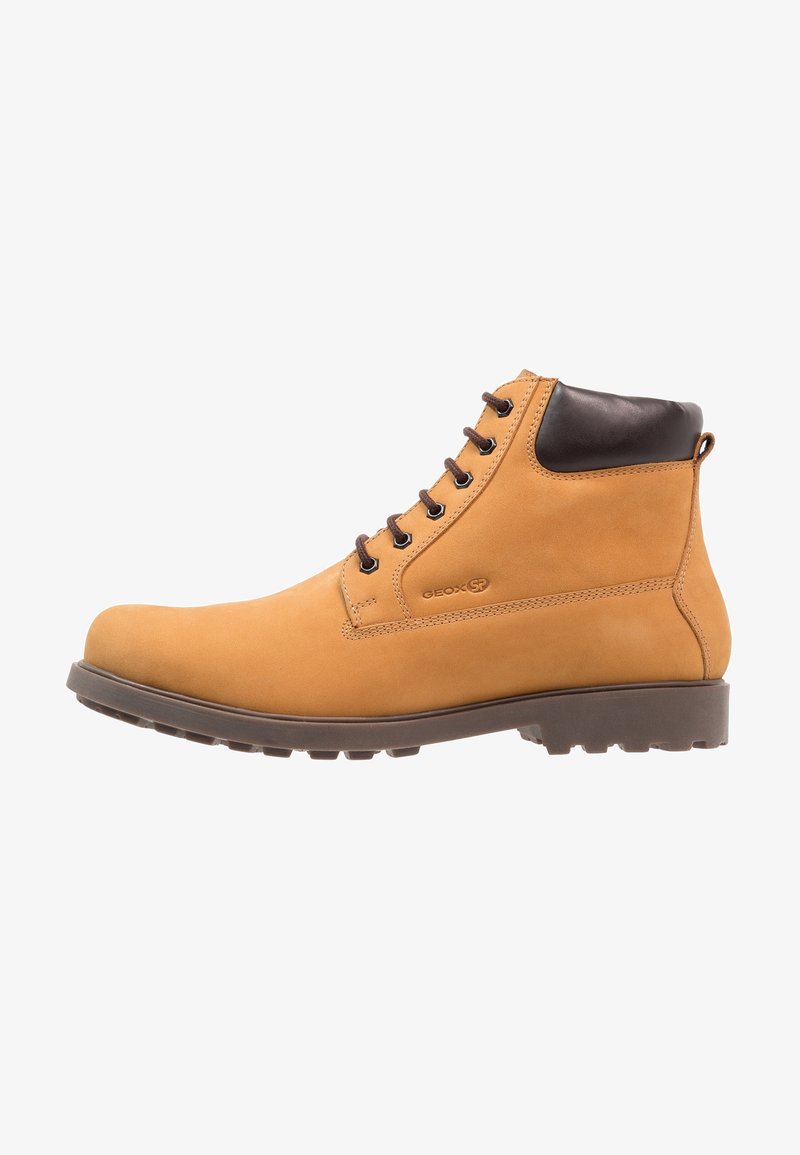 Bottes cheville en cuir fauve avec un bout rond, des accents marron au niveau du col et une semelle robuste avec des rainures profondes pour une meilleure traction.