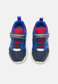 Baskets synthétiques bleues et navy avec des accents rouges, des panneaux en maille et une sangle Velcro. Présente des détails blancs et argentés sur la semelle et la languette.