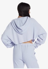 Himmelblauer, verkürzter Hoodie aus geribbeltem Material mit großer Kapuze und elastischen Bündchen, kombiniert mit passenden, gerippten Sweatpants.