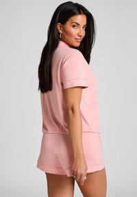 Roze loungewear set bestaande uit een T-shirt met korte mouwen en bijpassende shorts. Zacht materiaal, relaxte pasvorm, met een gladde textuur en subtiele zoomdetails.