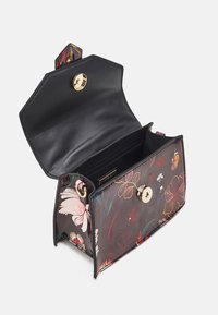 Svart läderhandväska med blommönster och guldfärgat spänne. Har en sexkantig form och ett rymligt inre med en dragkedjeficka.