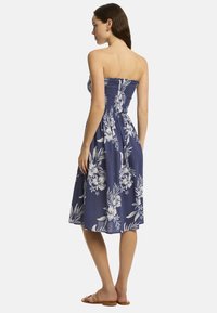 Abito smanicato, lungo fino al ginocchio, di colore blu navy, con corpino arricciato e motivi floreali bianchi. Realizzato in tessuto leggero con una vestibilità comoda.