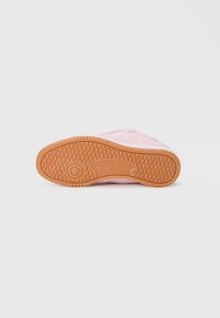 Reebok tenisice s ružičastim gornjim dijelom, bijelim detaljima i teksturiranom gumiranom potplatom u svijetlosmeđoj boji, s kružnim logotipom na donjem dijelu.