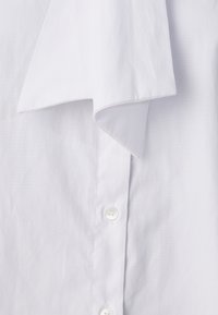 Camicia da uomo bianca in cotone con colletto a punta, texture liscia e cinque bottoni lungo la parte anteriore.