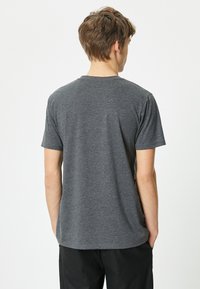 Grå bomulds T-shirt med korte ærmer og rund hals. Glat tekstur, minimal detaljer, standard pasform. Ingen synlige logoer eller mønstre.