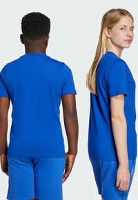 To personer iført matchende blå bomull t-skjorter og shorts, som viser fram den enkle, ensfargede og klassiske crew neck-designen.