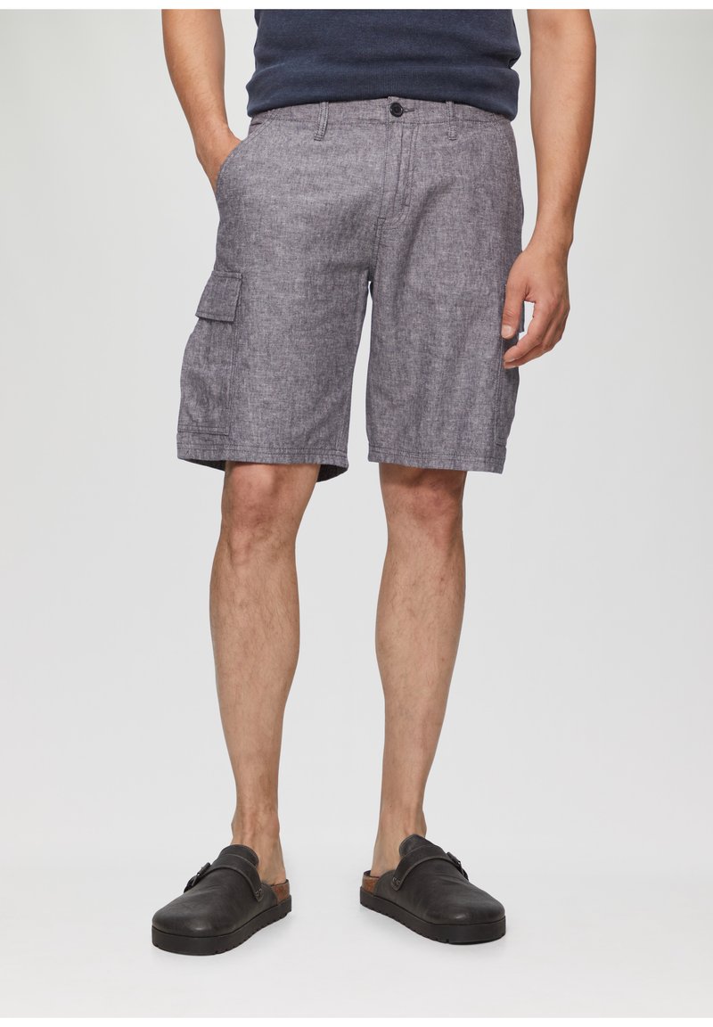 Graue Cargo-Shorts aus strukturiertem Material, mit Seitentaschen und Knopfverschluss. Getragen mit schwarzen Slippern.