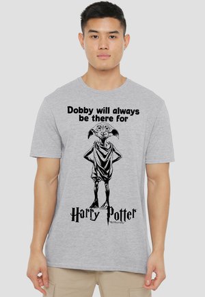 Young man wearing a gray t-shirt with a black illustration of Dobby and text "Dobby will always be there for Harry Potter."
