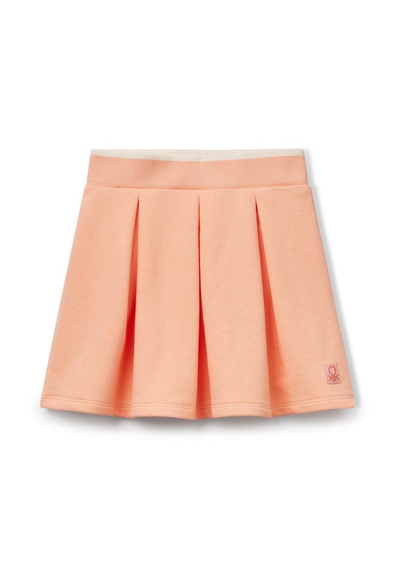 Perzikkleurige plissérok van zacht materiaal, met een brede elastische tailleband en een klein logo-opdruk aan de zijkant. Glad textuur.