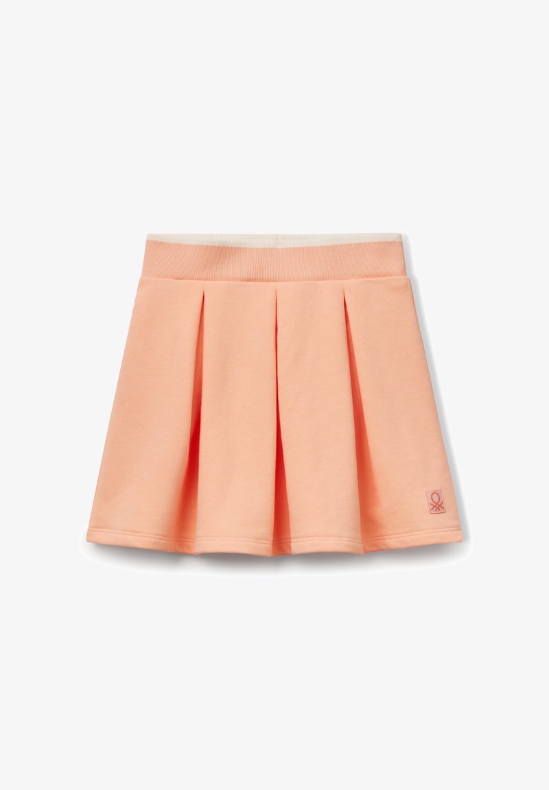 Perzikkleurige plissérok van zacht materiaal, met een brede elastische tailleband en een klein logo-opdruk aan de zijkant. Glad textuur.