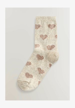 Chaussettes montantes en tricot beige clair avec des motifs de cœurs marron éparpillés. Dotées d'un talon et d'un orteil renforcés pour plus de durabilité. Texture douce.