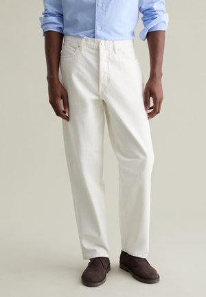 White denim trousers with a straight-leg cut, featuring a zipper fly, front pockets, and subtle stitching details, paired with brown shoes.