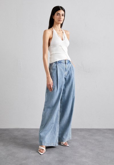 White ribbed halter top with lace trim, wide-legged blue denim jeans, and strappy white heels. Smooth textures, neutral colors, relaxed fit.