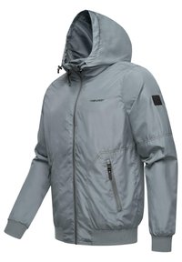 Chaqueta con capucha gris claro, con cremallera frontal, puños acanalados, dos bolsillos laterales con cremallera y un logo en el pecho izquierdo. Textura de tela suave.
