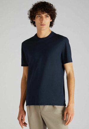 Camiseta de algodón azul marino con cuello redondo y mangas cortas. Textura suave, corte relajado, diseño minimalista sin estampados ni logotipos.