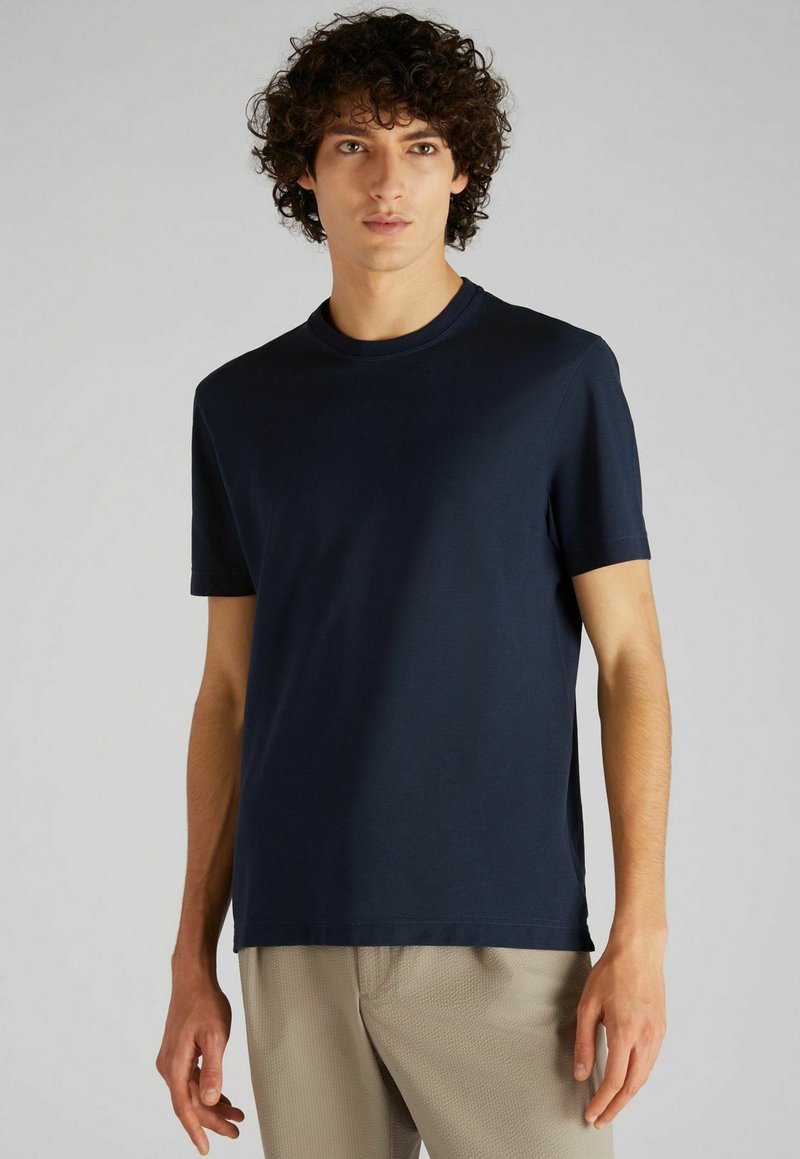 T-shirt en coton bleu marine avec un col rond et des manches courtes. Texture lisse, coupe décontractée, design minimal sans motifs ni logos.