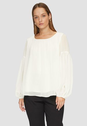 Blouse blanche avec un col rond, des manches longues en voile et des poignets froncés. Fabriquée en tissu léger, elle présente une coupe décontractée et une texture lisse.