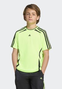Neon geltonas sportinis marškinėlis su juodais akcentais ir trimis juodomis juostelėmis ant pečių. Lengvas audinys, apvalus kaklas, trumpomis rankovėmis.